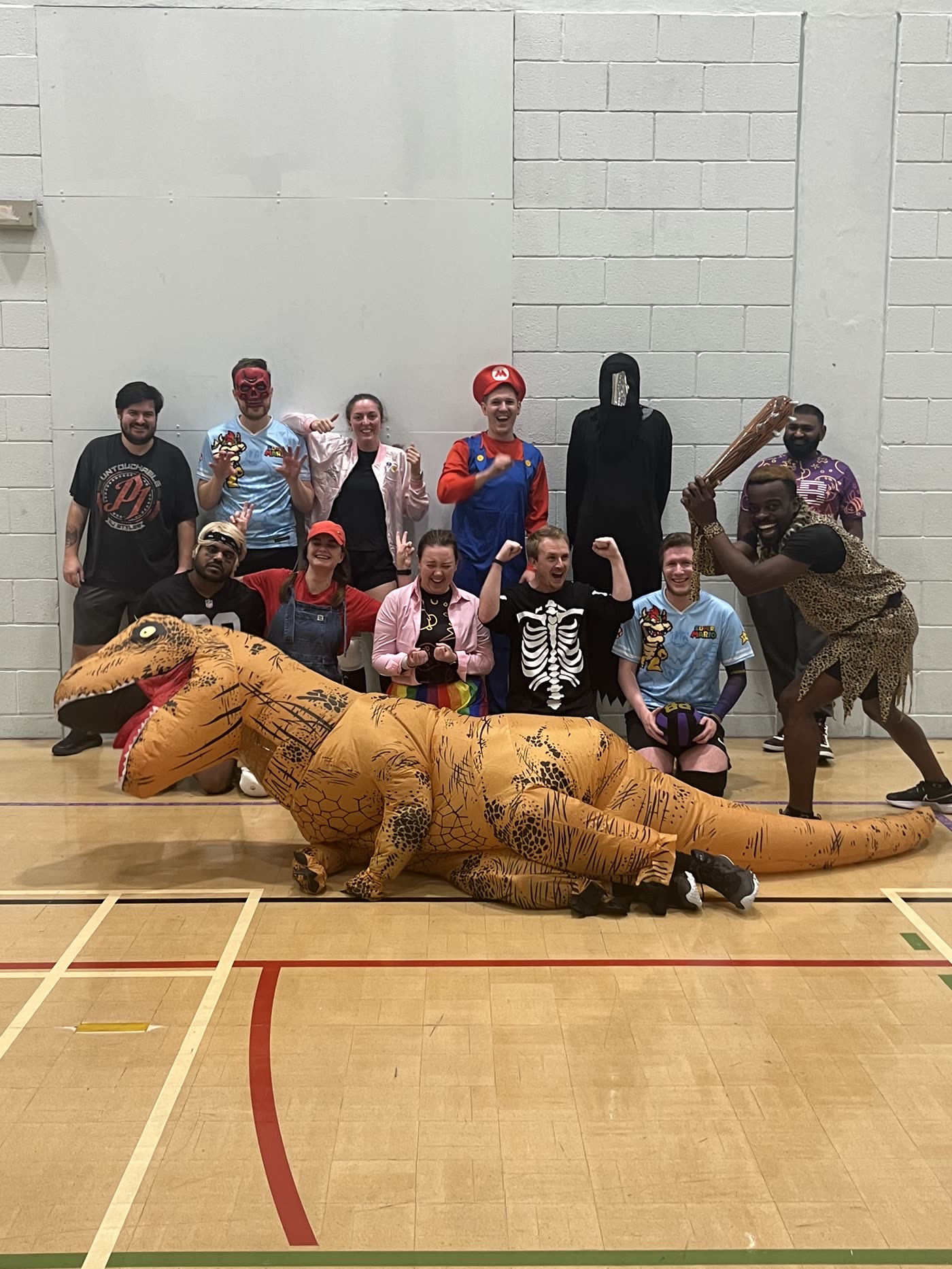 A fancy dress group photo with an inflatable dinosaur lying across the front