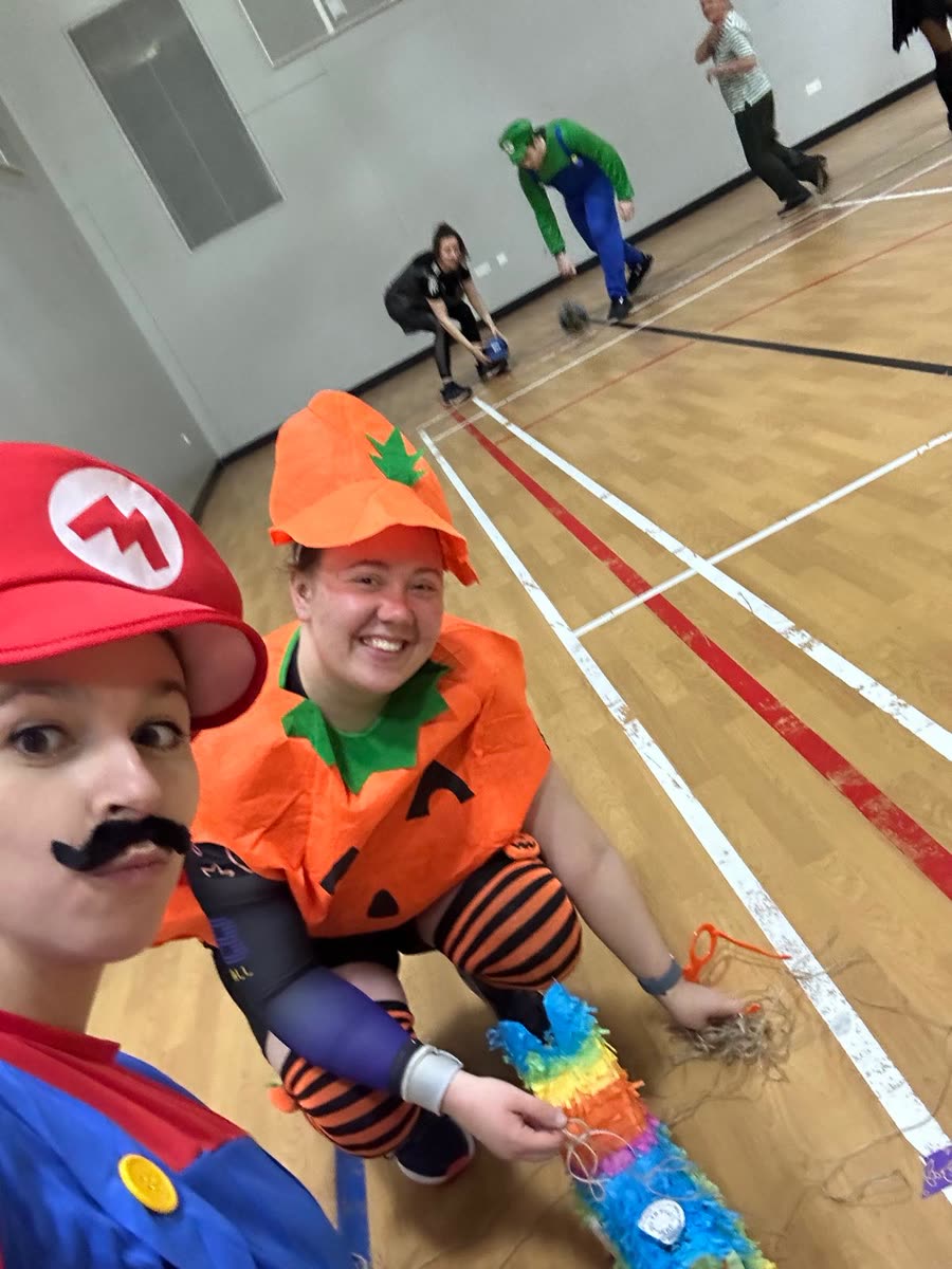 Two players dressed as Mario and a pumpkin taking a selfie on court
